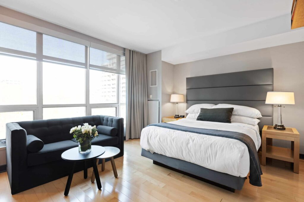 Ljust hotellrum med bekvämt säng, sittgrupp och stora fönster mot staden. Perfekt för en avkopplande övernattning.