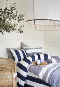 Ljust sovrum med blåvita sängkläder och maritim stil, naturnära inredning, perfekt för skandinavisk sovrumssättning.