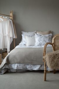 Ljust sovrum med vita och beige sängkläder, rumsdesign med naturliga material och inredning.
