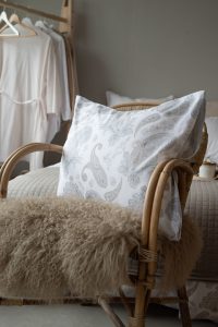Ljusstol med kuddar och pläd i naturliga material i elegant hem.