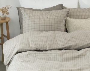 Mjuka sängkläder i beige rutmönster för en mysig sovrumsstil.