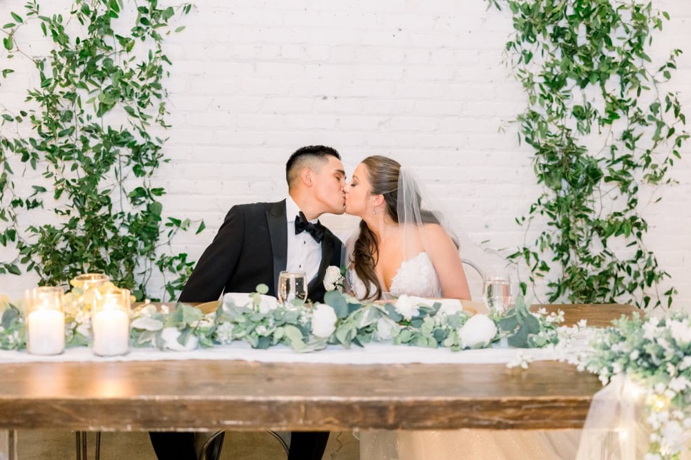 Bride and Groom sharing a kiss at the head table during wedding reception in Denver Colorado