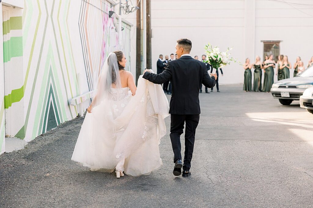 Bride and Groom walking up to bridal party groom is holding her dress and flowers