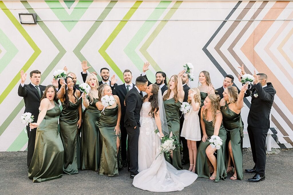 Bride and Groom sharing a kiss and bridal party is cheering behind them