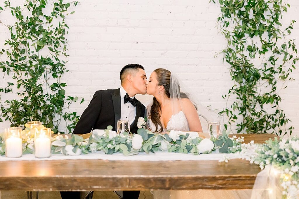 Bride and Groom sharing a kiss at their sweetheart table