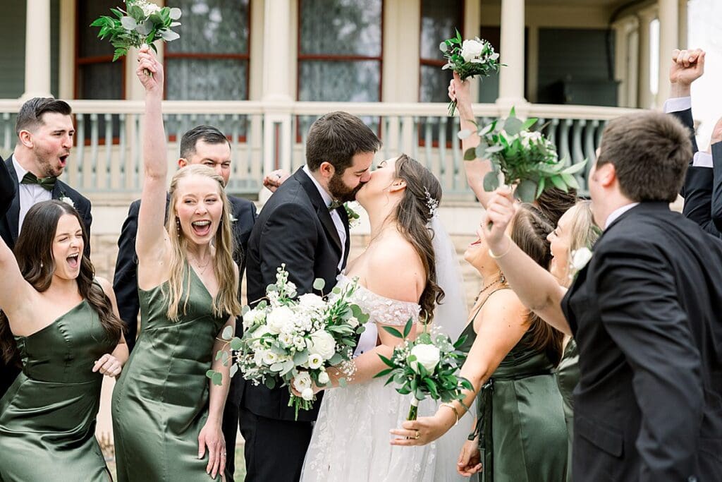 Bride and Groom sharing a kiss while bridal party cheers