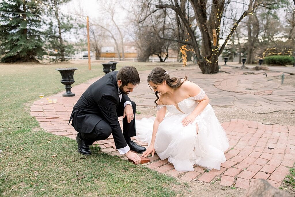 Bride and Groom placing their brick on the ground of the tapestry house