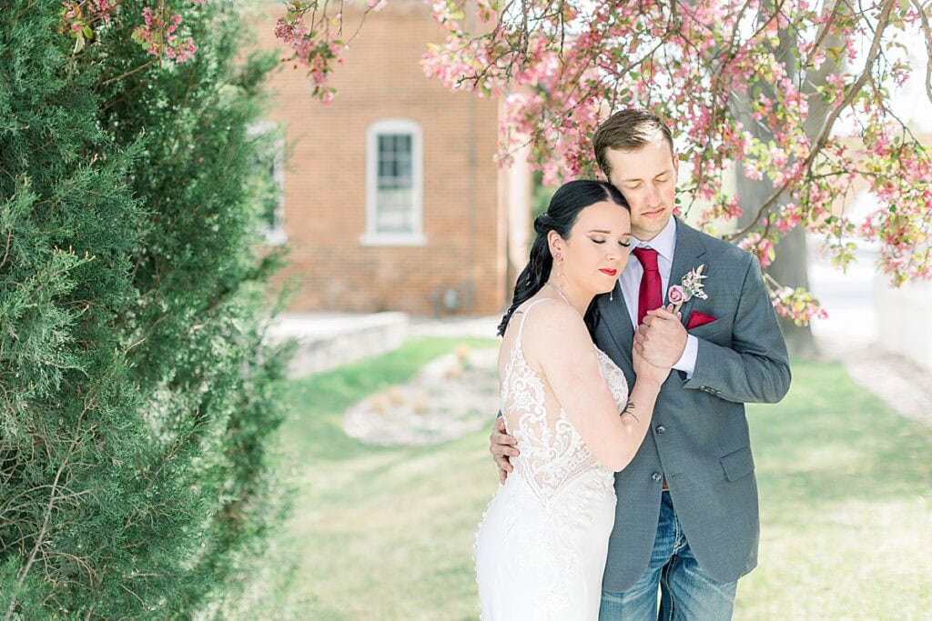 Bride and Groom cuddling under a pink flower tree