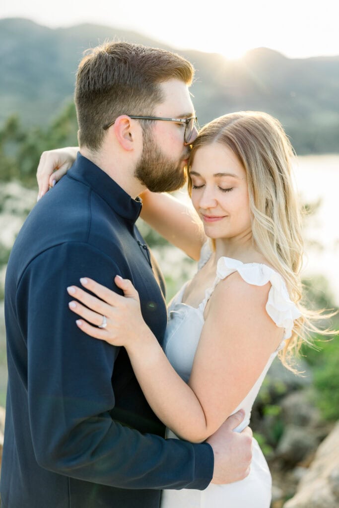 Guy kissing girls temple while they cuddle in close