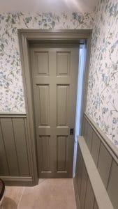 1. Traditional painted interior door with floral wallpaper and beadboard wainscoting.