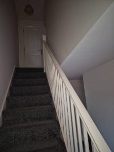 Bright staircase with grey carpet and white railing, interior home decorating by S Bond Decorating.