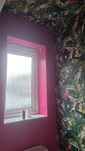 Bright pink and tropical-themed wallpaper in a living space by S Bond Decorating, expert interior wall painting.