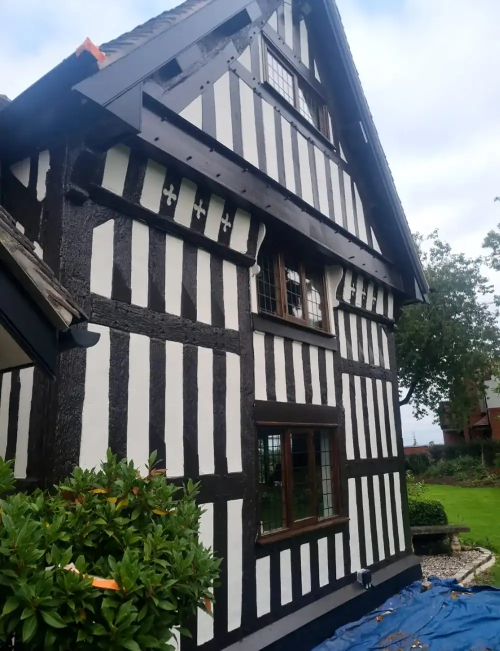 Intricate black and white Tudor-style house exterior with decorative timber framing.
