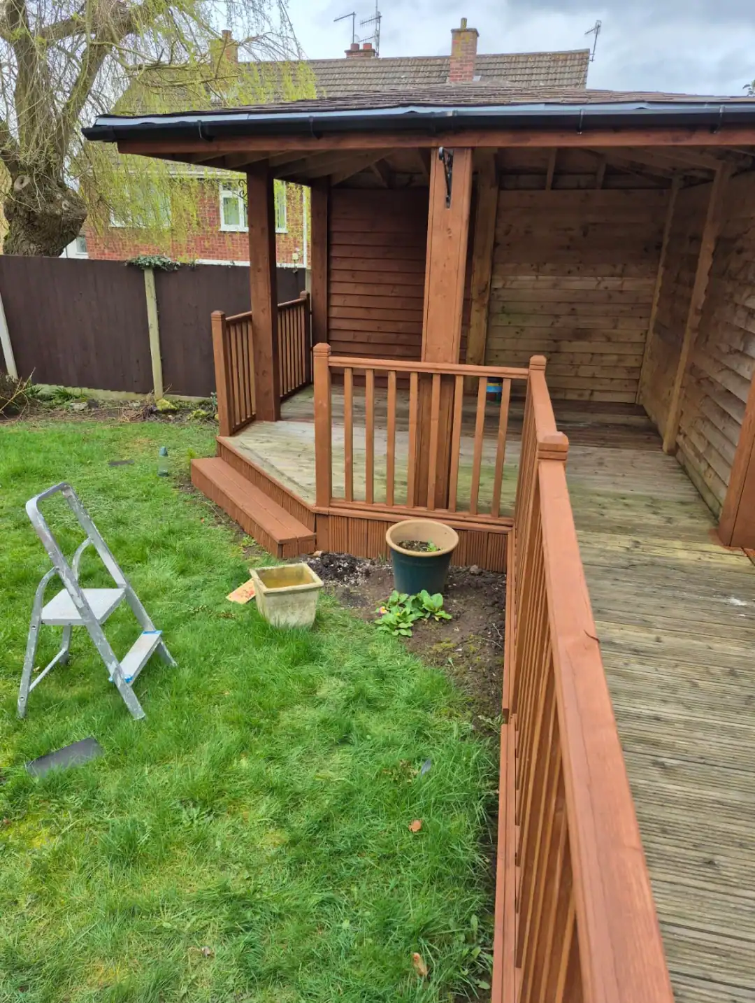 Decorated wooden garden shed with newly stained fencing and decking | S Bond Decorating.