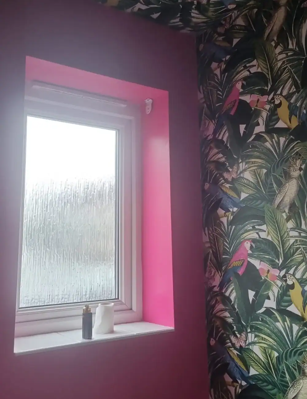 Bright pink painted window niche with tropical bird wallpaper on surrounding wall, enhancing home decor and interior style.
