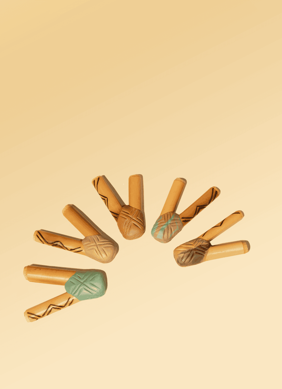 Colorful wooden rainsticks with tribal patterns, traditional musical instruments used in Shaman Hape Circle rituals, arranged in a semi-circle on a beige background.