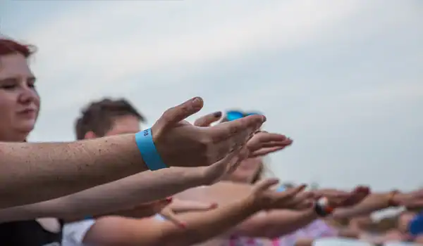 People with outstretched hands in the air outdoors.