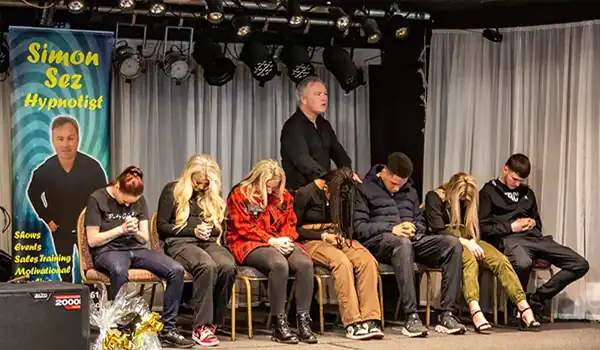 Hypnotist performing with participants on stage