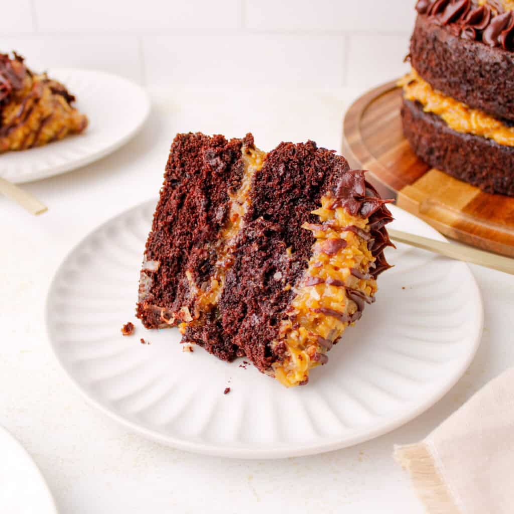 Slice of Homemade German chocolate cake with coconut pecan filling and ganache border.