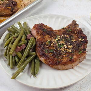Juicy oven baked pork chops on plate with green beans.