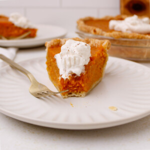 A slice of sweet potato pie with whipped cream.