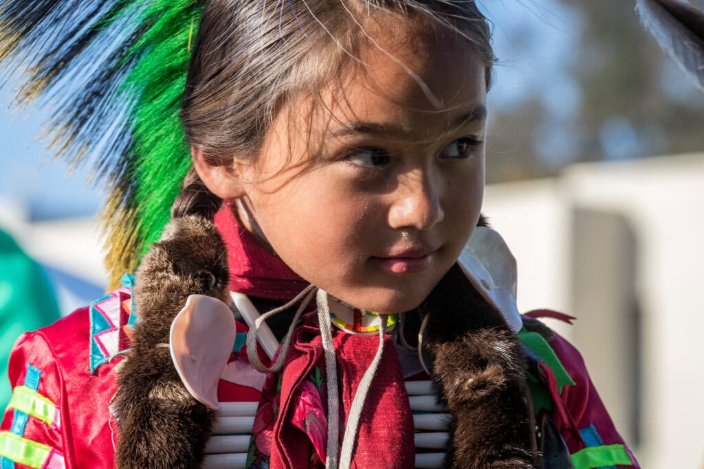 Children of Indigenous culture wearing traditional regalia for singing and community celebration at Singing Feather Ministries.