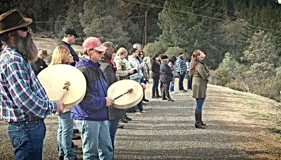 A group of people engaged in worship and prayer outdoors at Singing Feather Ministries.
