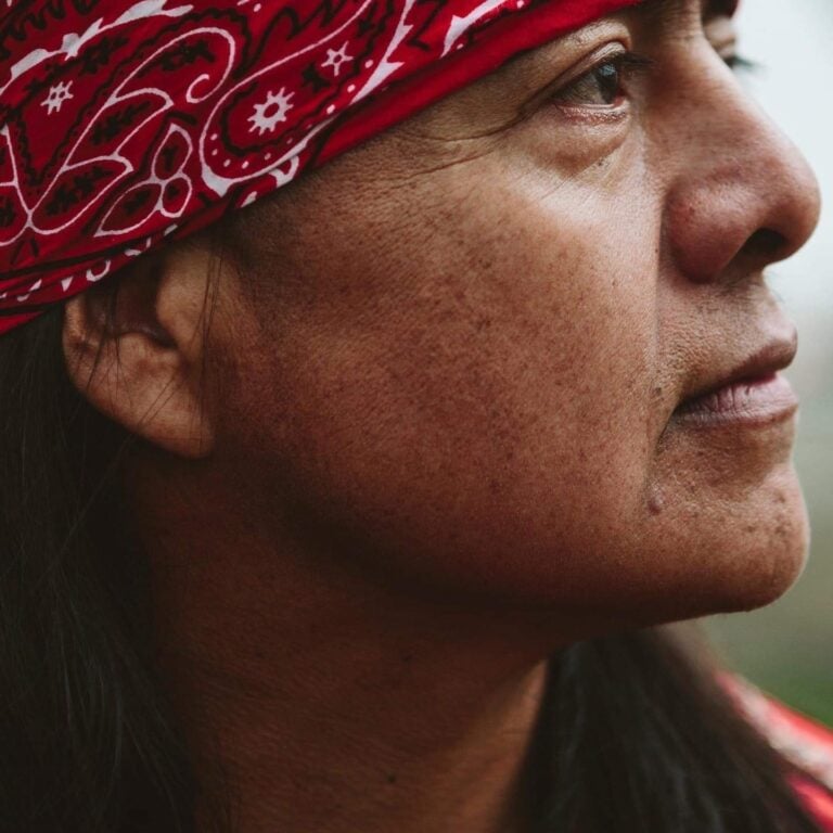 Wisdom and resilience of indigenous women, close-up of a woman wearing a red bandana, symbolizing strength and cultural heritage.