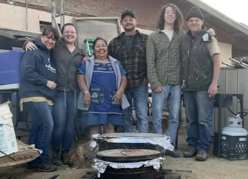 Volunteers cooking outdoors at Singing Feather Ministries community event.