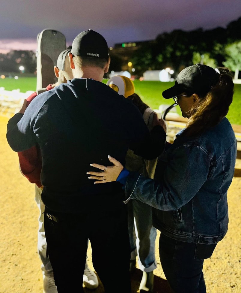 Alt text: People praying together outdoors at twilight, fostering faith and community connection.