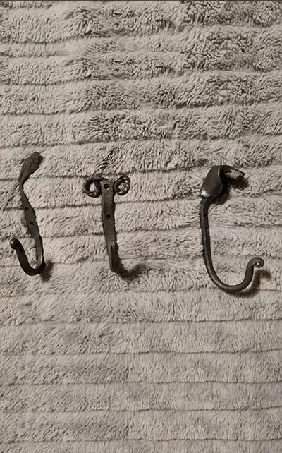 Three metal hooks on textured fabric surface.