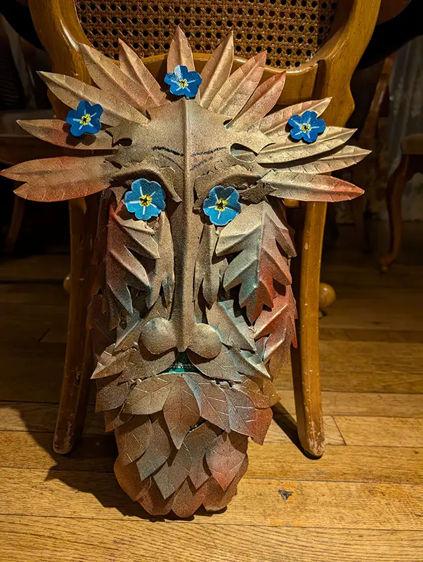 Decorative leaf and flower face mask on chair.