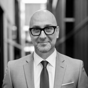 Professional portrait of a man in a suit and glasses at Skyler Construction.