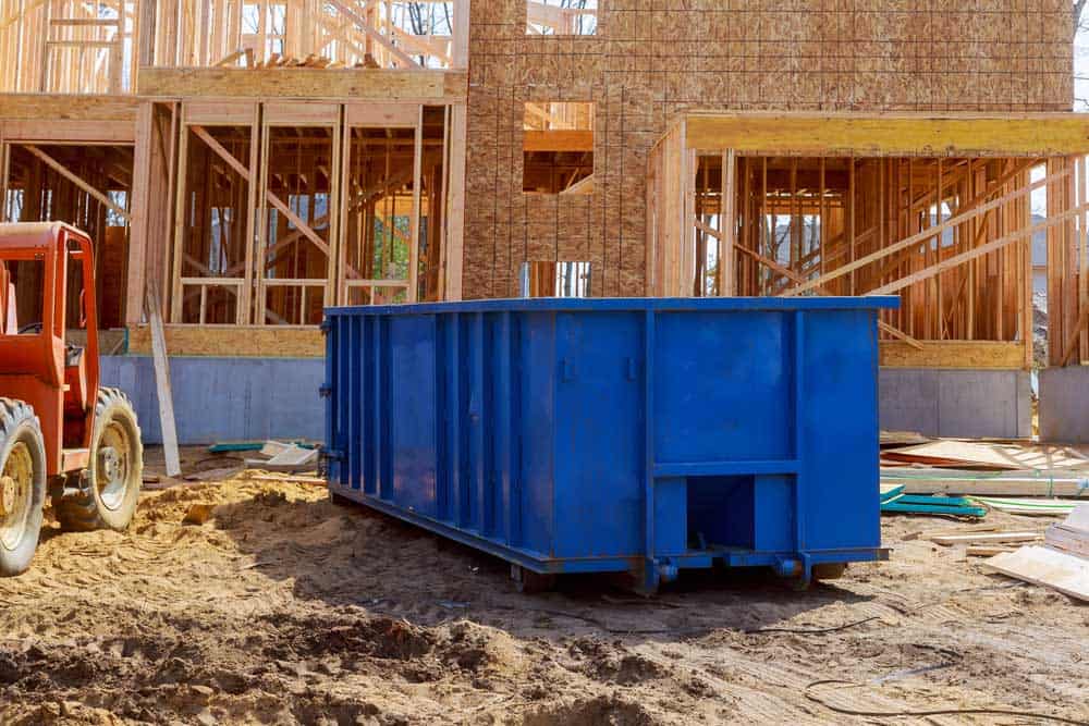 Blue construction waste container on building site.