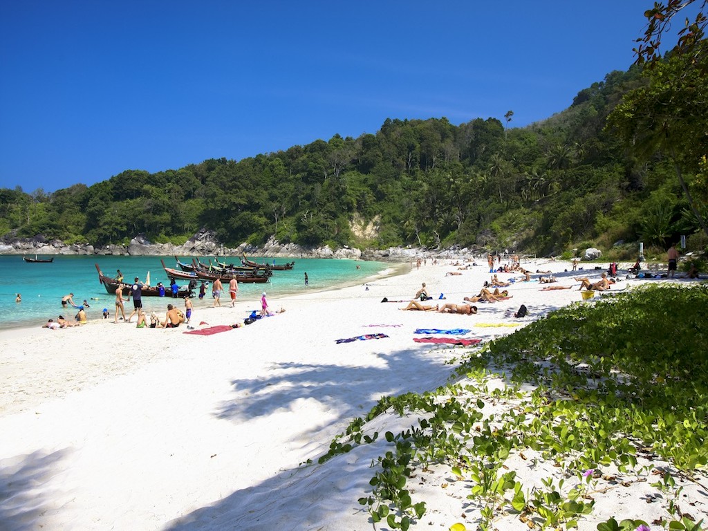Patong Beach in Phuket featuring pristine white sand, clear blue waters, and lush green hills in the.
