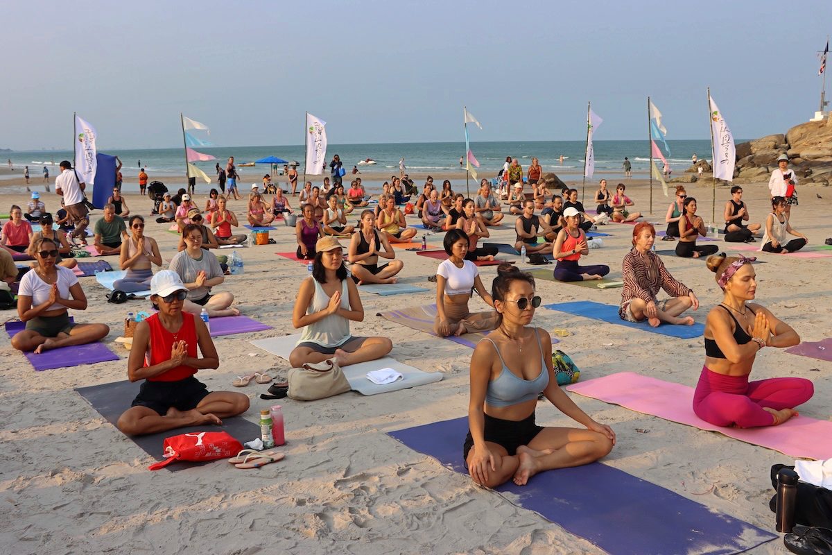 Yoga practitioners practicing on the beach during Hua Hin Beach Yoga Morning Event.