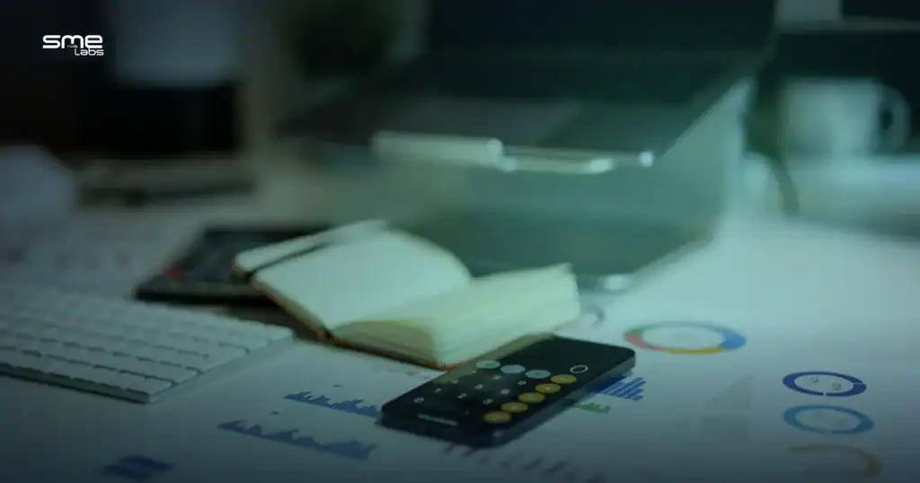 Desk with a laptop, calculator and financial charts representing a CCIE exam cost budget