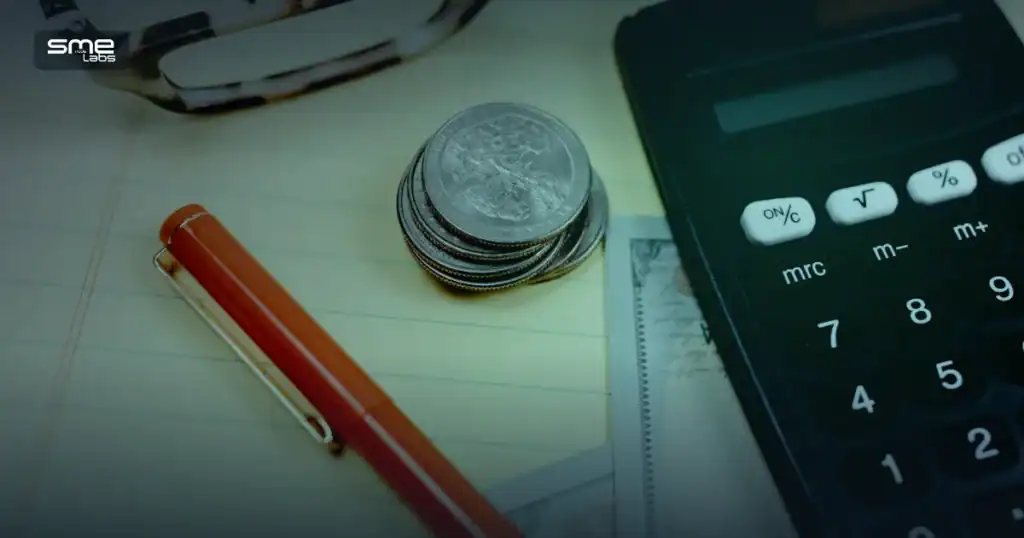 Calculator, coins and cash on a desk, representing budgeting for the CCNA exam cost