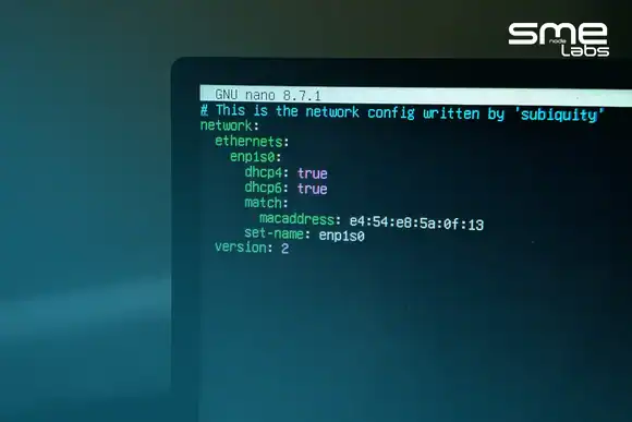 A Linux network configuration file open on a screen, showing an ethernet interface set to dhcp4 true, with SMEnode Labs cyan fading in from the bottom-left corner.