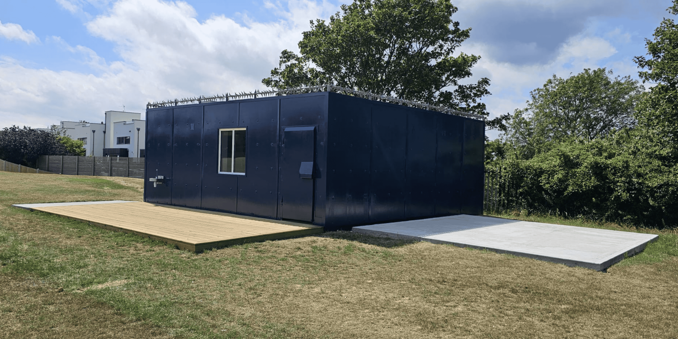 Blue modular building unit with two windows on grassy field at Kings School