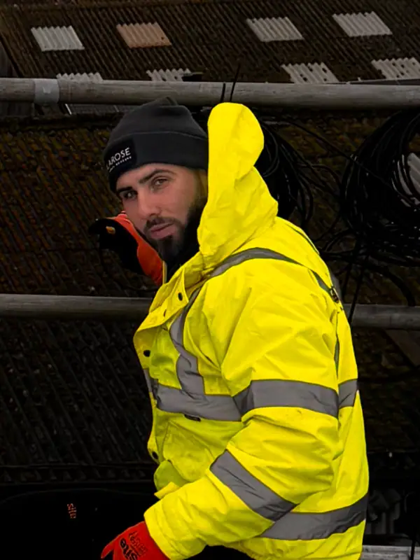 Highly visible solar technician in yellow safety jacket working near solar panels, representing renewable energy solutions.