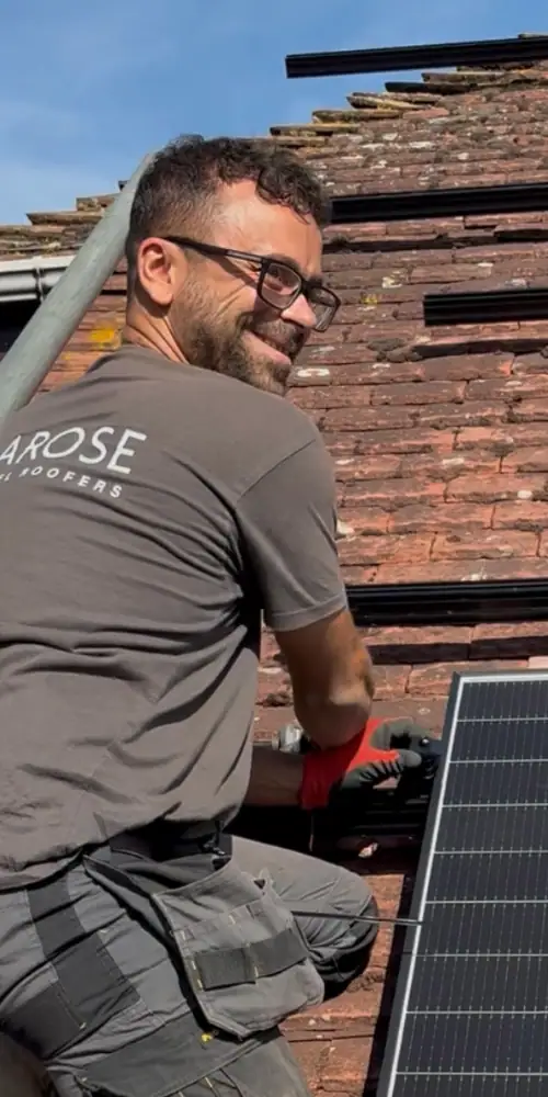Experienced solar panel installer working on a residential roof in Kent, installing high-efficiency solar panels to maximize renewable energy production.