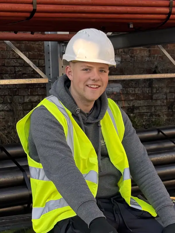 Expert-solar-roofers about us page of Oscar a SOLAROSE roofer siiting in the sun with hivis and a hard hat on