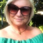 Kobieta z blond włosami i dużymi okularami słonecznymi na tle natury.