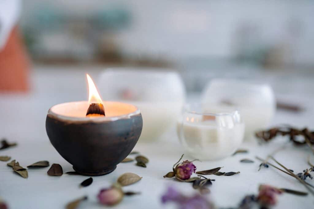 pexels-photo-7233912-7233912 Warm candle flame in ceramic holder with dried flowers on table.