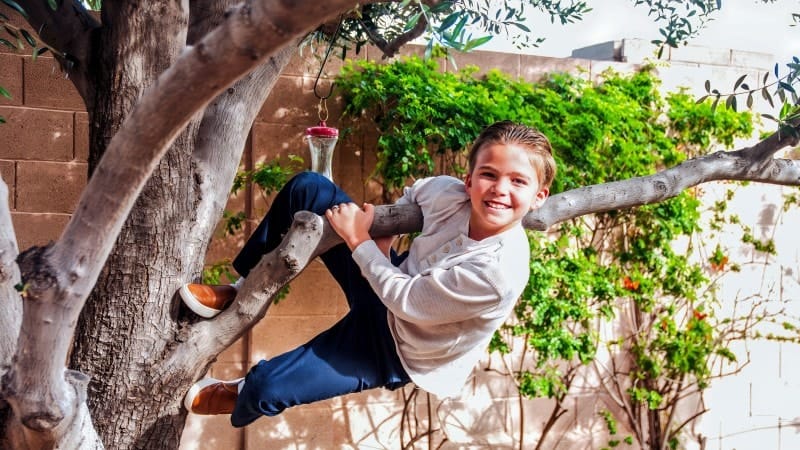 Joyful Girl Playing on Tree Branch