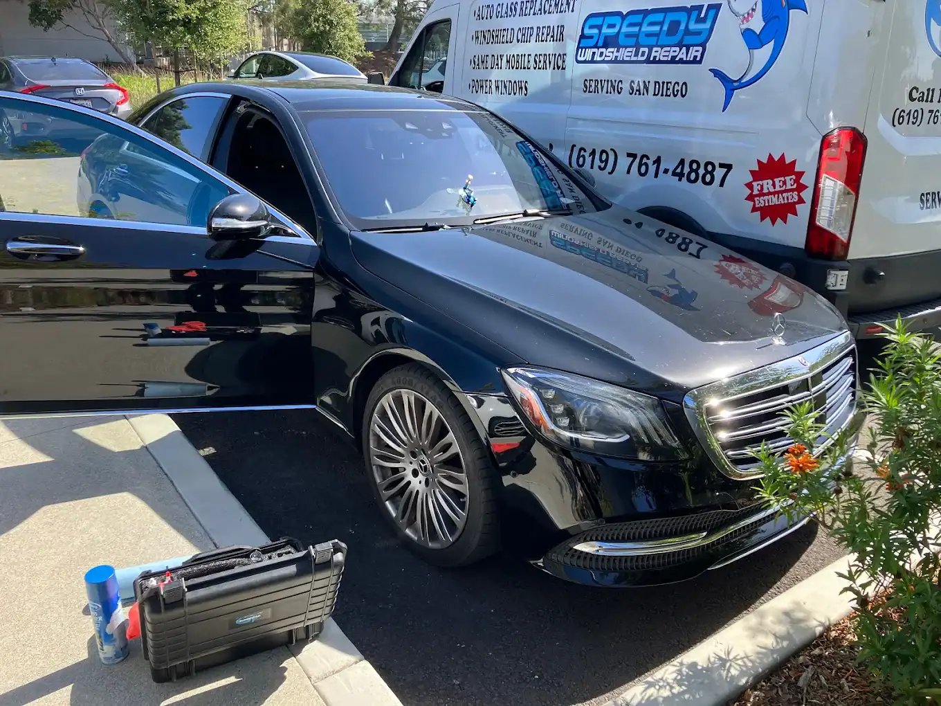 Black Mercedes-Benz S-Class beside the Speedy Windshield Repair mobile van during an on-site windshield replacement