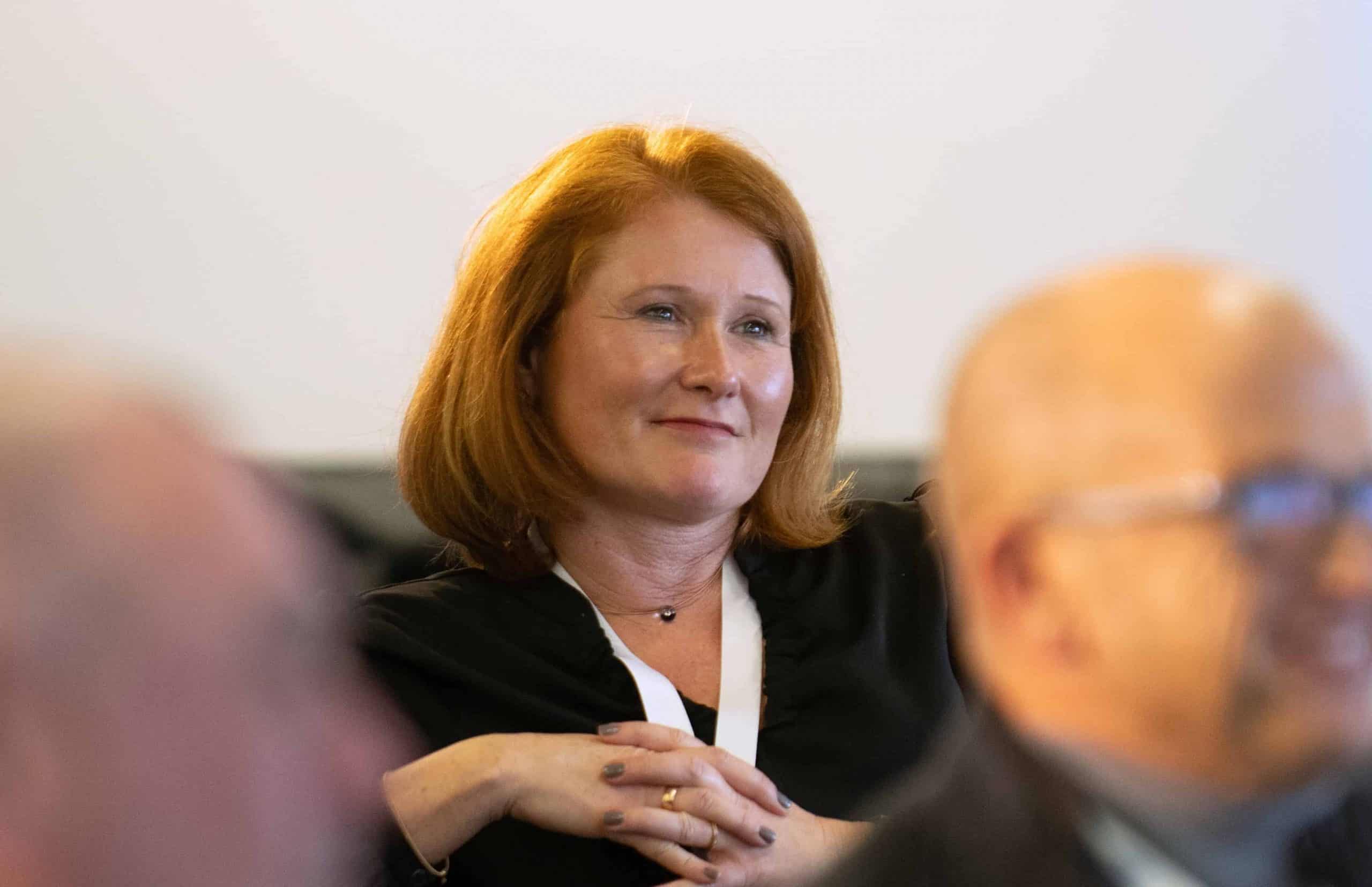 Frau bei einer Diskussion auf einer Veranstaltung, Fokus auf Gesichtsausdruck.