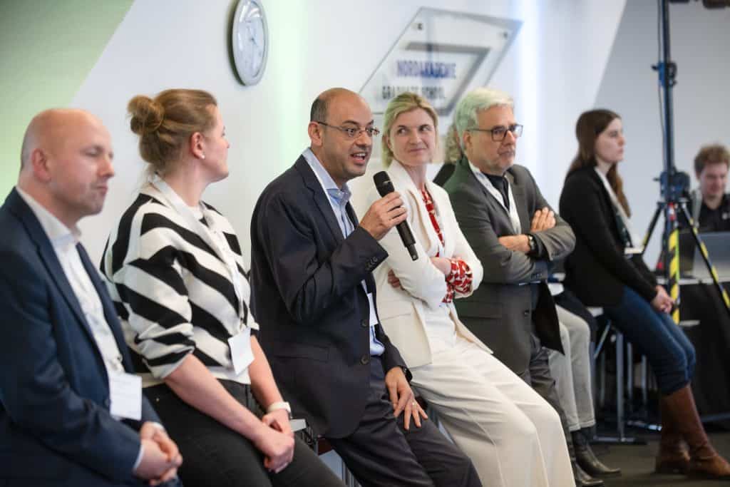 Diskussion bei Konferenz mit Experten und Publikum in moderner Umgebung.