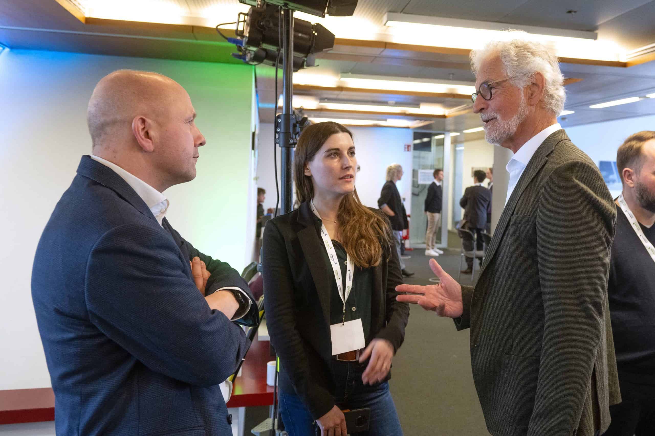 Drei Personen im Gespräch bei einer Konferenz, professionelle Diskussion.